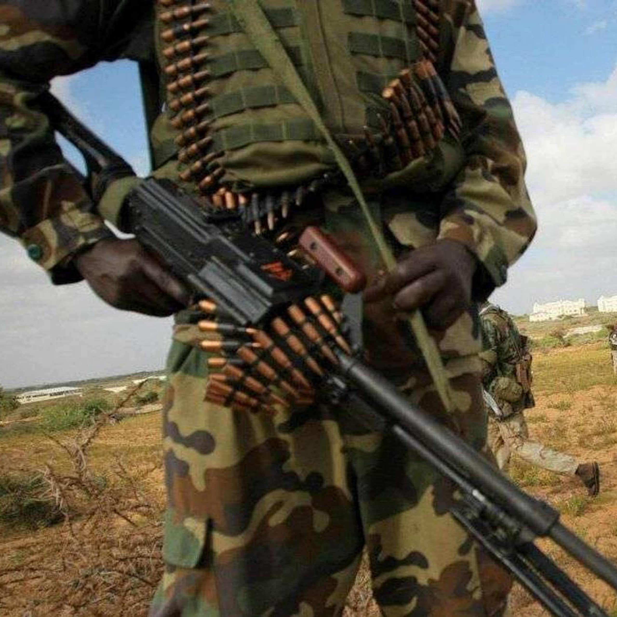 People in camouflage and khaki uniforms, carrying weapons