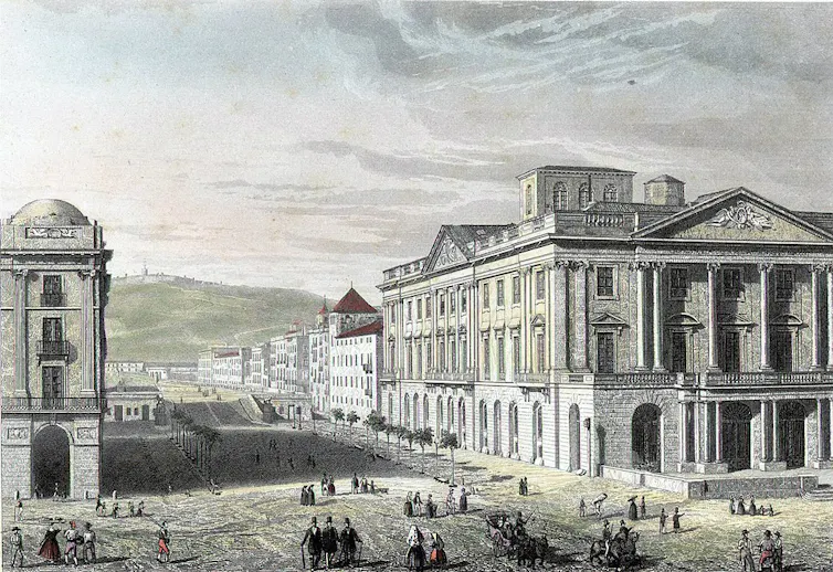 Vista de les façanes principal i lateral de l'edifici de la Llotja. Gent passejant pel Passeig d'Isabel II. A l'esquerra, les Porxos d'en Xifré.