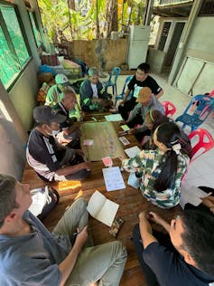 People from Thai communities sit around table discussing plans.