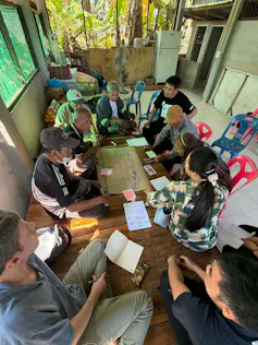 People from Thai communities sit around table discussing plans.