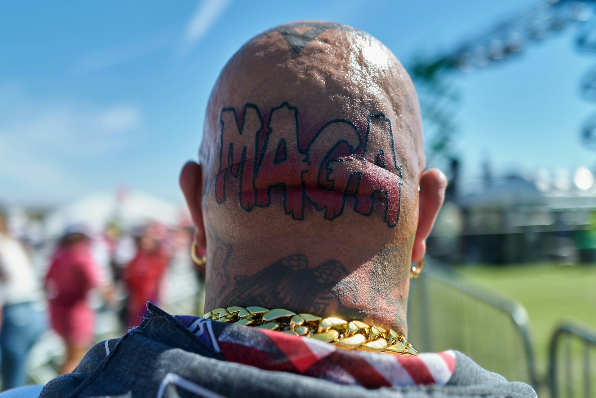 The back of a bald man's head with a tattoo reading: MAGA