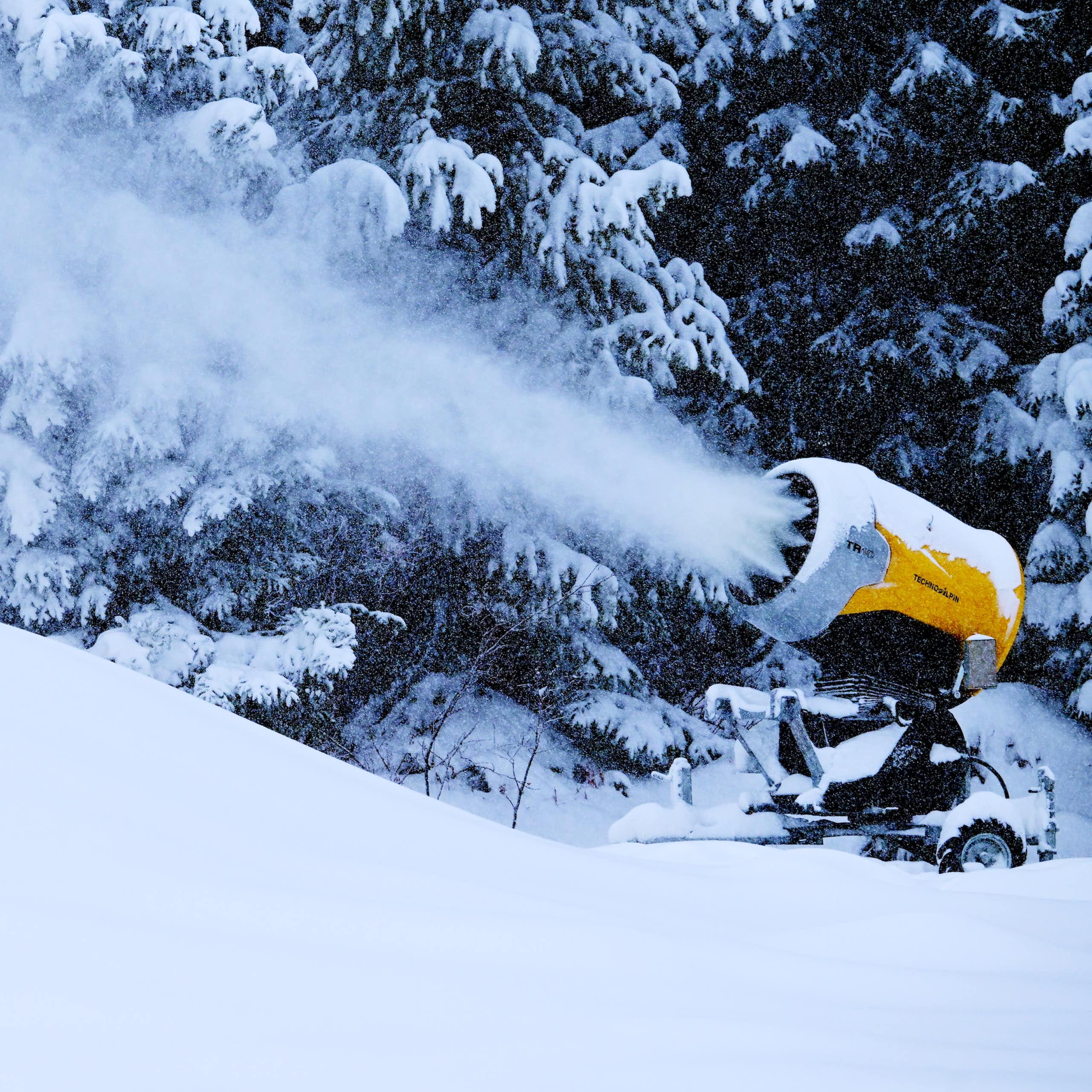 A snowmaking machine blows out snow at a ski resort.