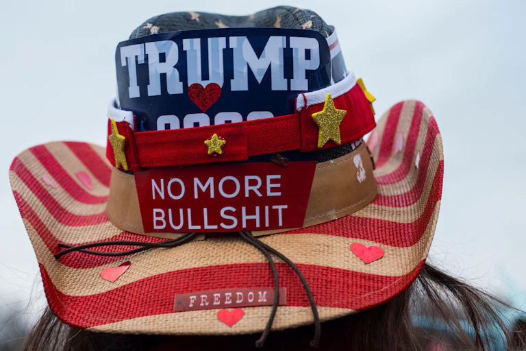 A Trump supporter wears a hat dclaring his views.