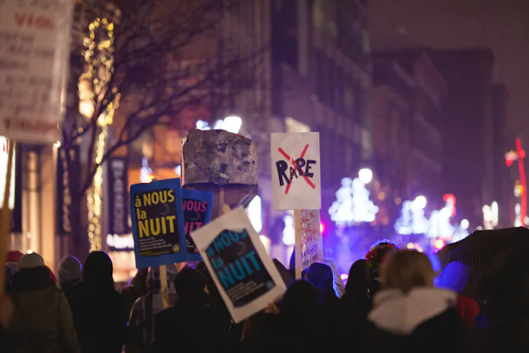 Un groupe de femmes marchant dans les rues, certaines brandissant des pancartes de protestation telles que « no rape » (non au viol) et « a nous la nuit » (la nuit est à nous)