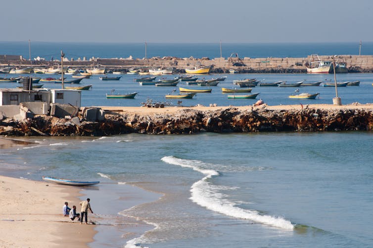 Gaza’s once-growing financial system is nearing overall cave in 1 Gazan fishermen haul in their net on a beach next to a harbour/