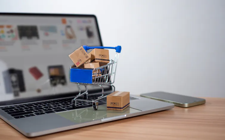 maptop with online shopping on screen and mini trolley with tiny boxes of goods