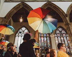 Children raise rainbow-coloured umbrellas during an opera performance.