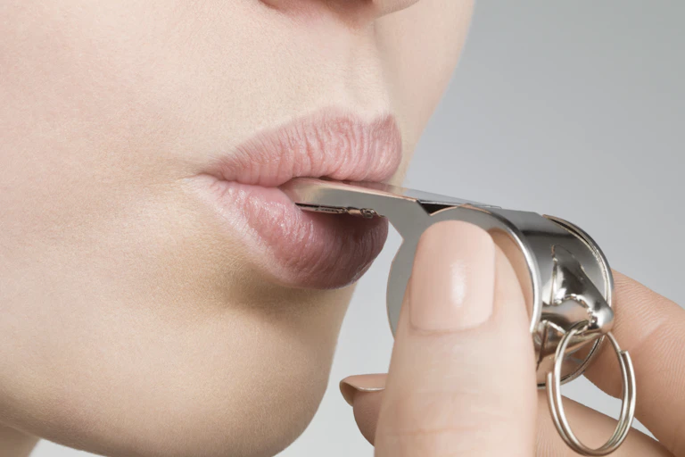 A close-up photo shows a woman blowing a whistle.