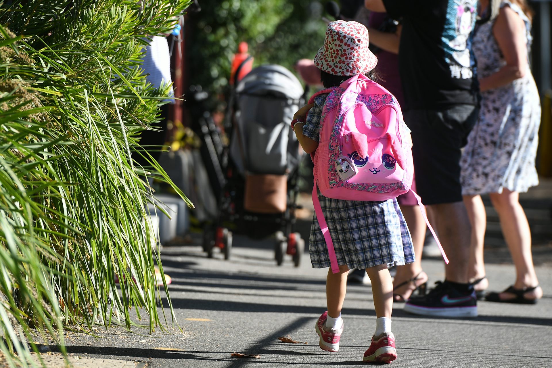 A young child walking in a back pack and uniform