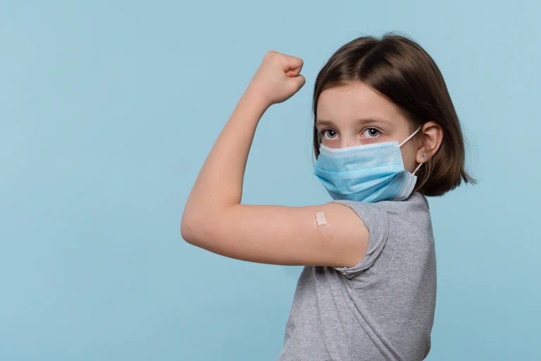 A young girl holding up her arm to show that she's been vaccinated.