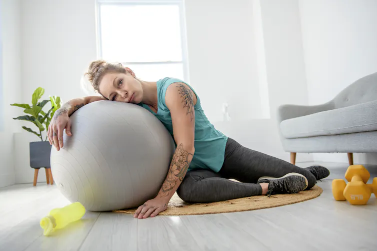 Woman flopped over an exercise ball in living room.