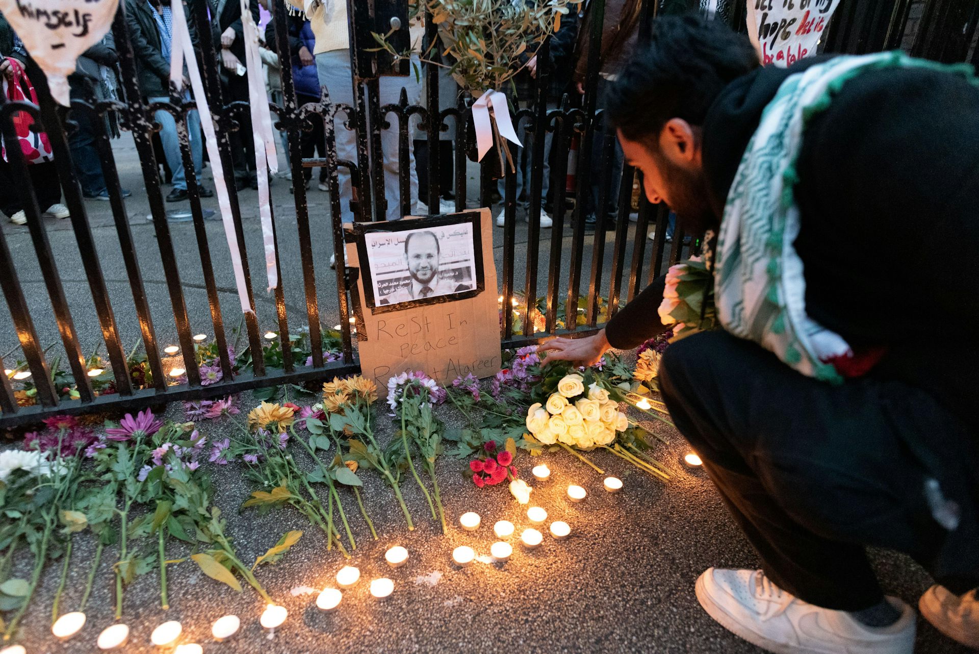 A student placing a flower at a vigil