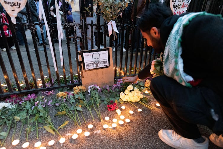 A student placing a flower at a vigil