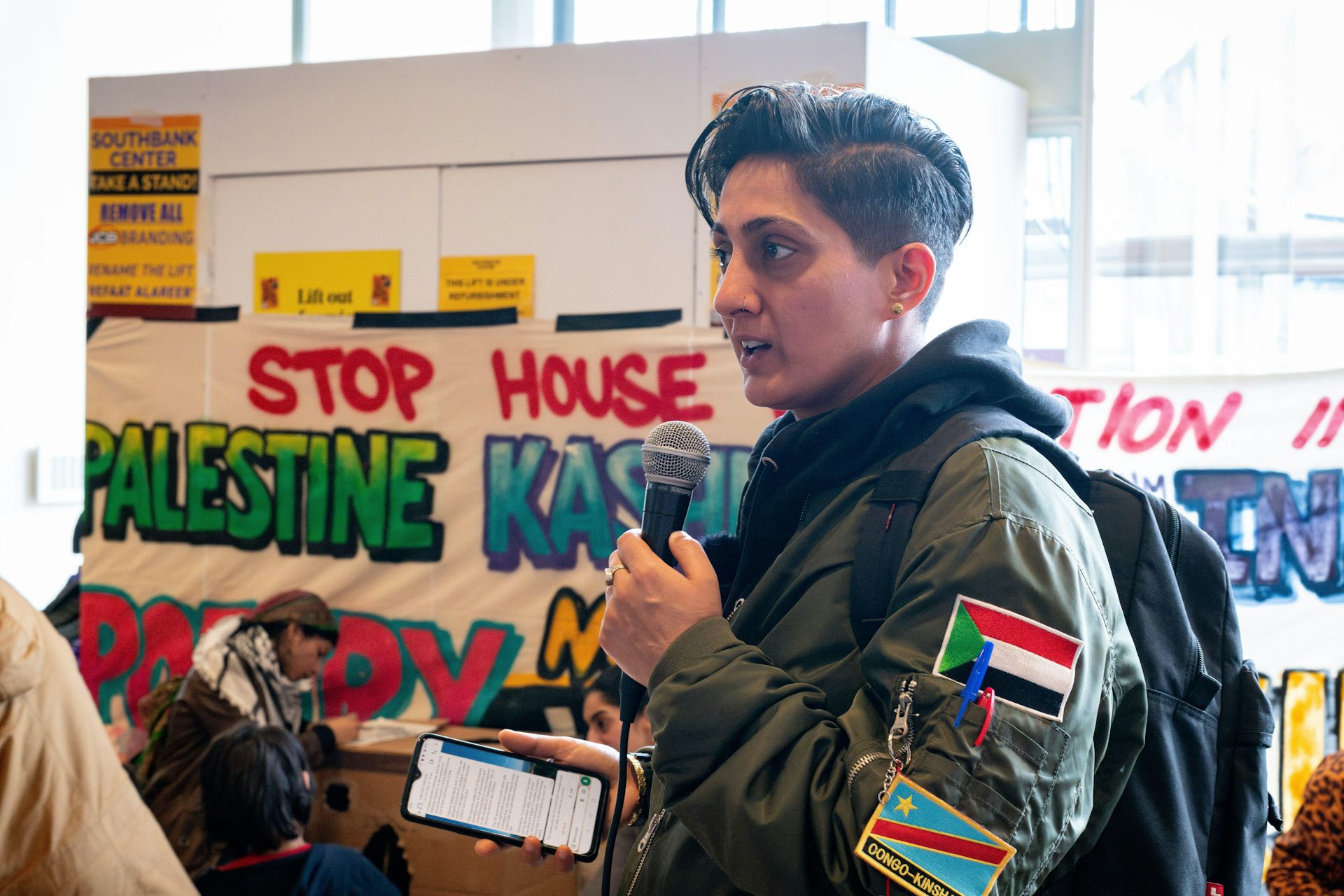 A poet wearing patches bearing the Palestine flag