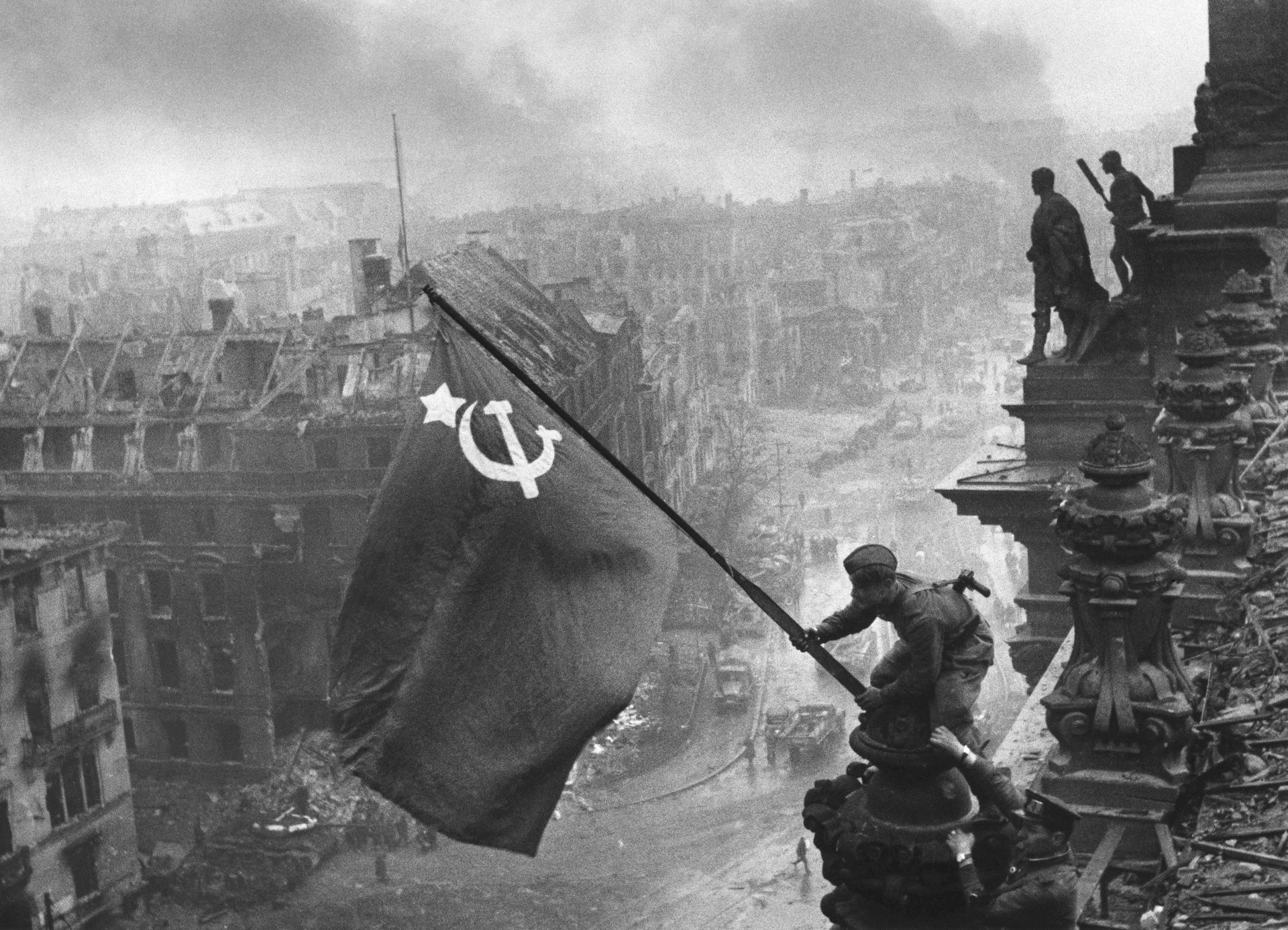 Dos soldados soviéticos colocando una bandera soviética en lo alto del edificio del Reichstag.