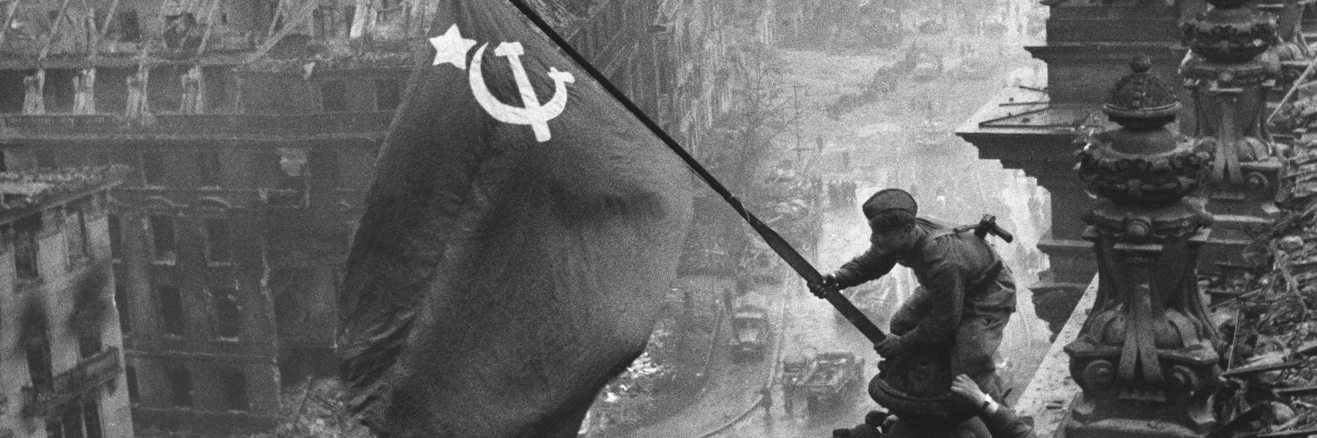 Dos soldados soviéticos colocando una bandera soviética en lo alto del edificio del Reichstag.