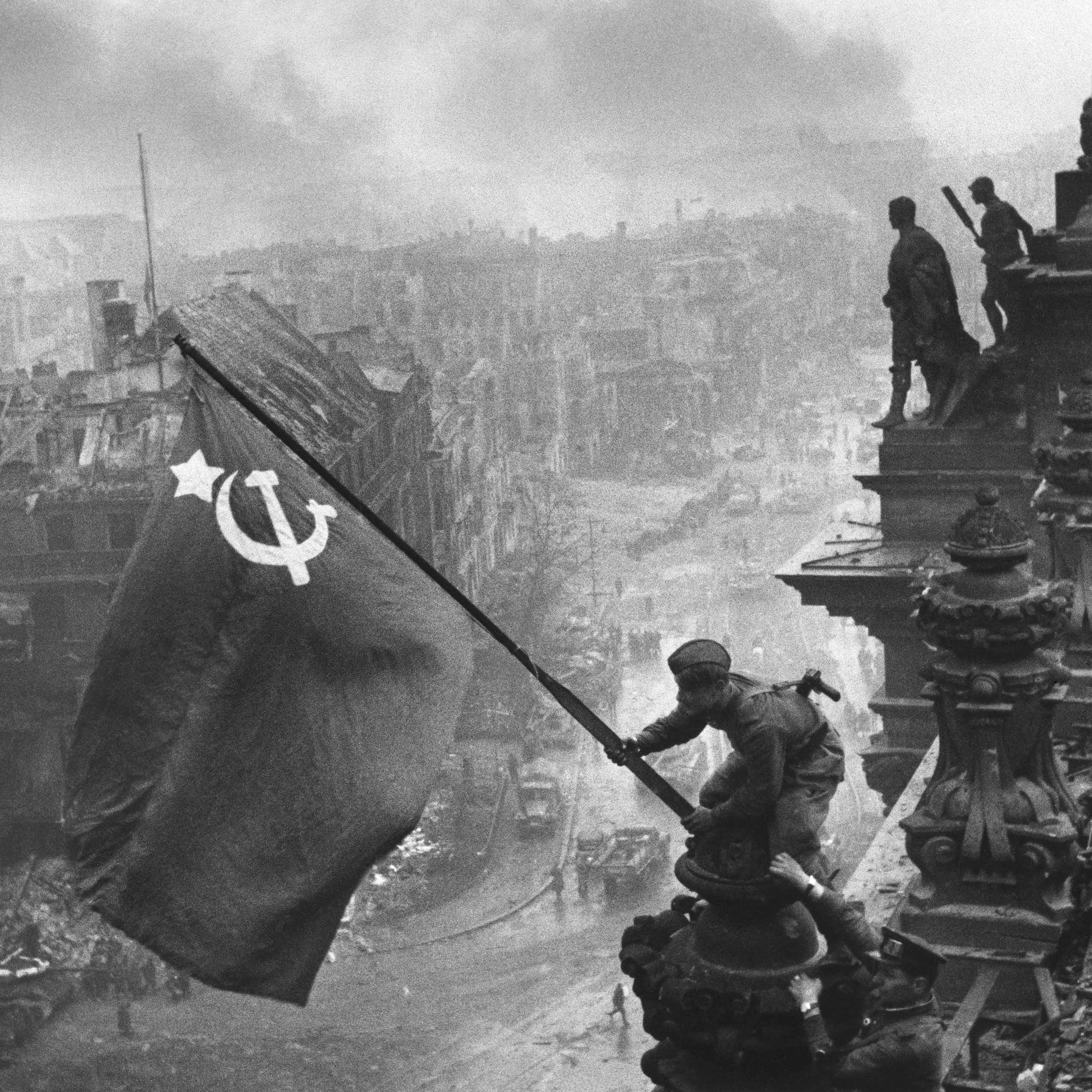 Dos soldados soviéticos colocando una bandera soviética en lo alto del edificio del Reichstag.