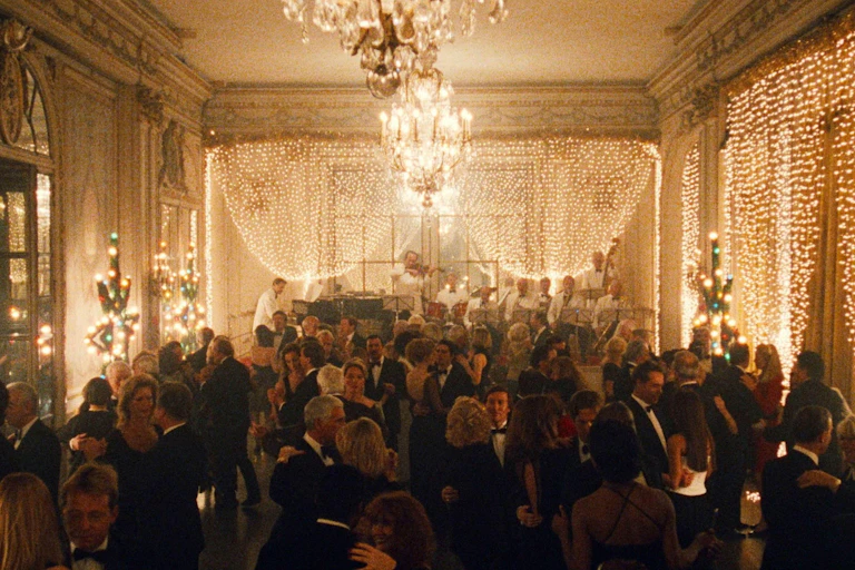 A large ballroom full of people decorated for Christmas with beautiful lighting.