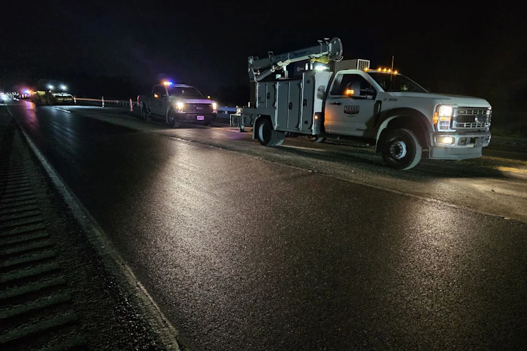 Several trucks driving next to an asphalt road.
