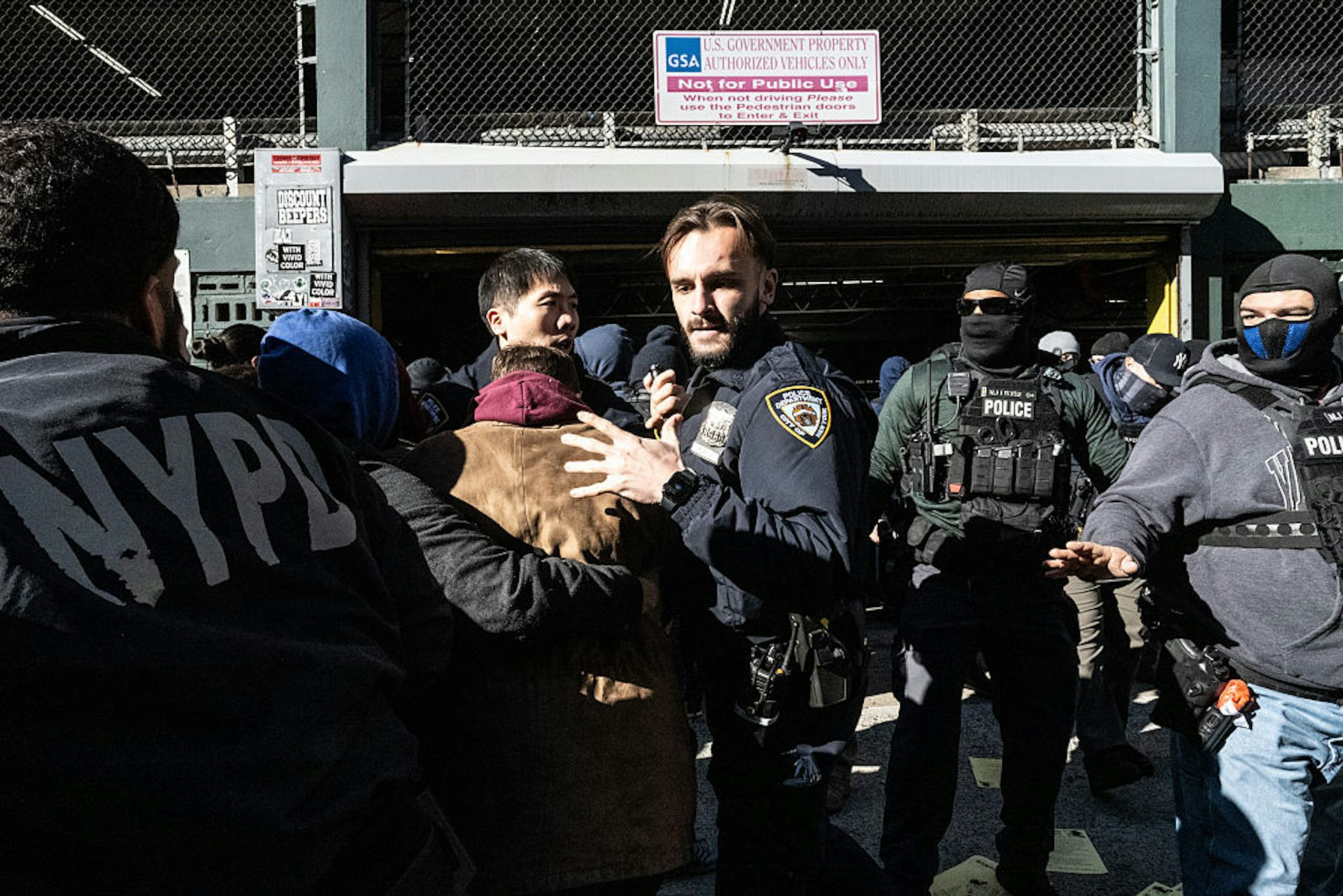 Uniformed police officers push back a crowd of people.