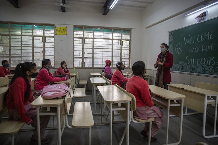 A teacher at the front of a class facing students.