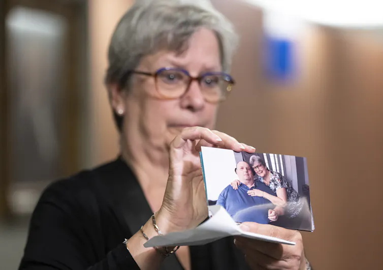 Una mujer con cabello gris y gafas, sosteniendo una fotografía.