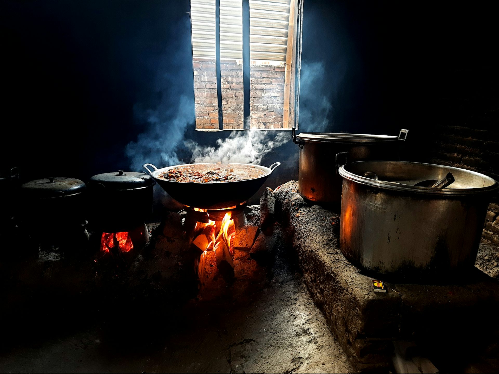 Kitchen with wood-fired stove creating white smoke