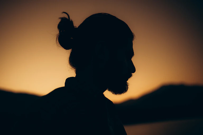 A silhouette of a man against a sunset sky