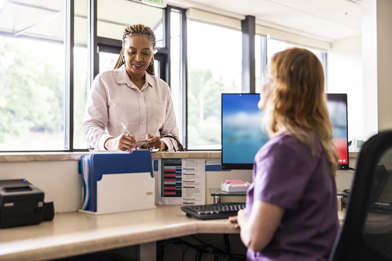 Female patient filling out form at doctor's office front desk