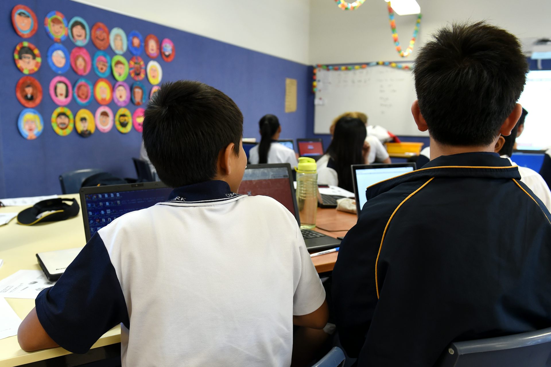 Students listen to their teacher in a classroom. 