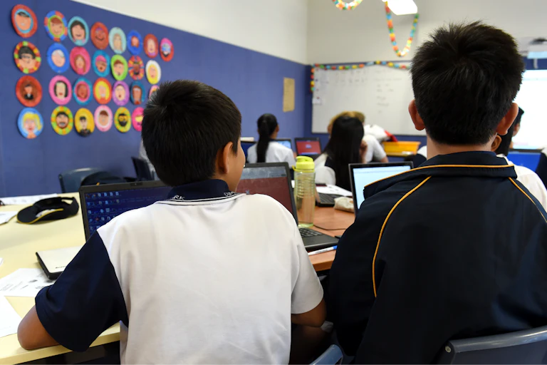 Students listen to their teacher in a classroom.