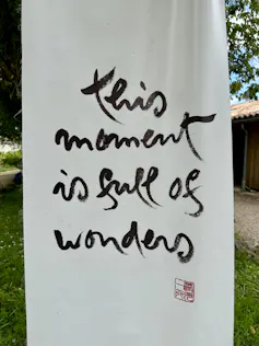 A white scroll with the words, 'This moment is full of wonders.'