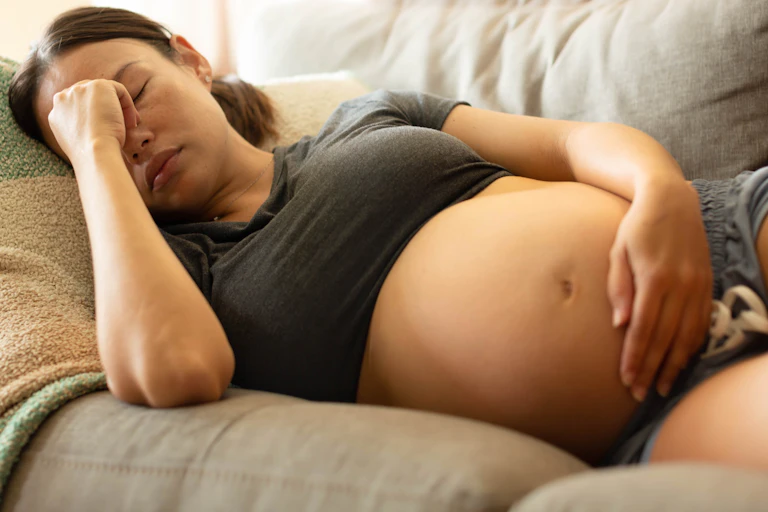 Tired pregnant woman pinches the bridge of her nose.