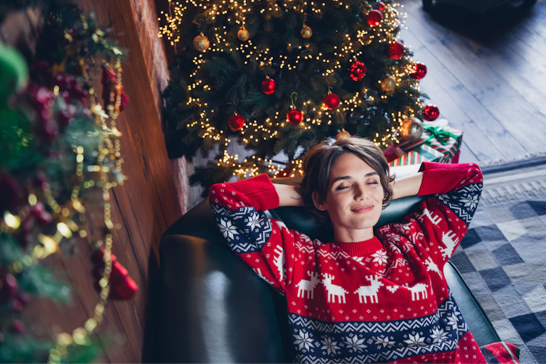 A happy young woman relaxing on a couch near a christmas tree