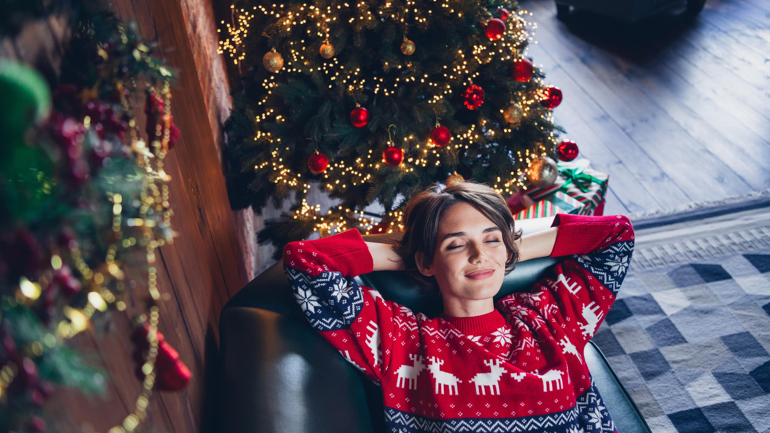 A happy young woman relaxing on a couch near a christmas tree