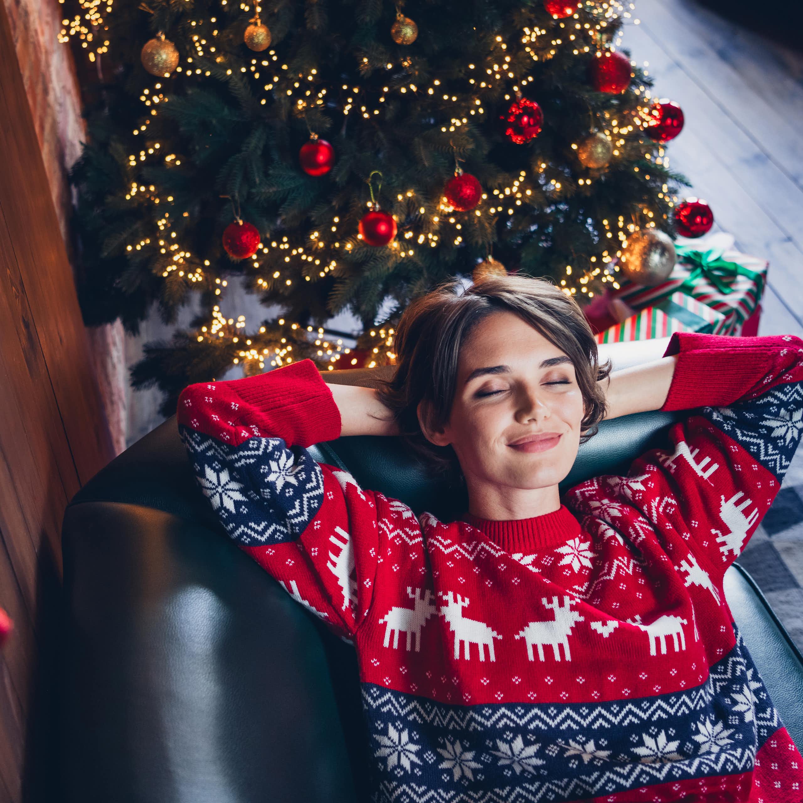 A happy young woman relaxing on a couch near a christmas tree