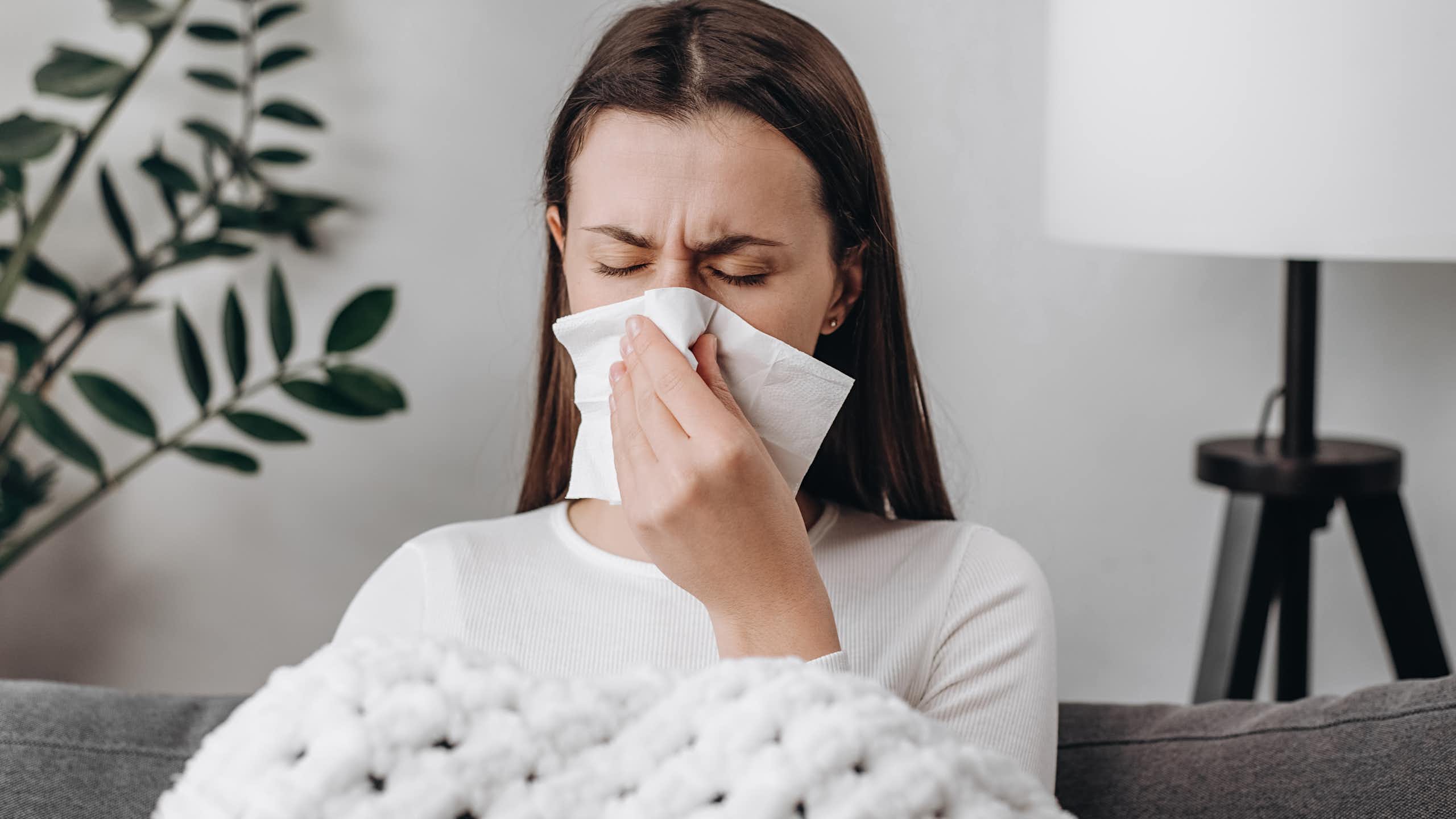 Una mujer enferma se suena la nariz.