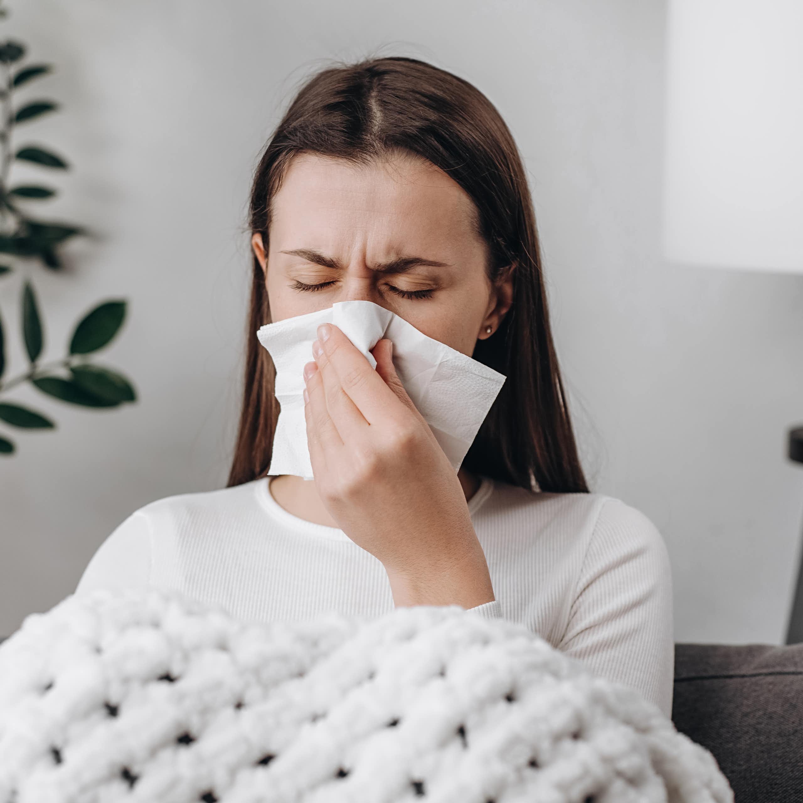 Una mujer enferma se suena la nariz.