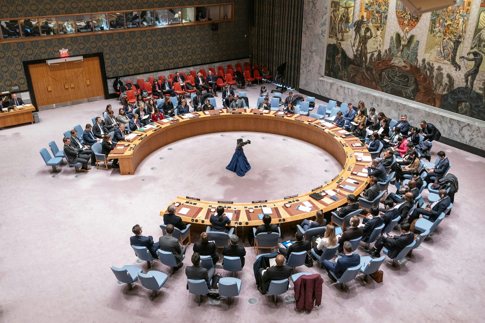 Vista cenital de una sala con asientos en torno a mesas dispuestas circularmente.