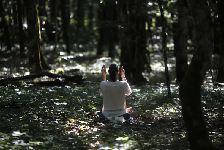 A woman meditates in the forest.