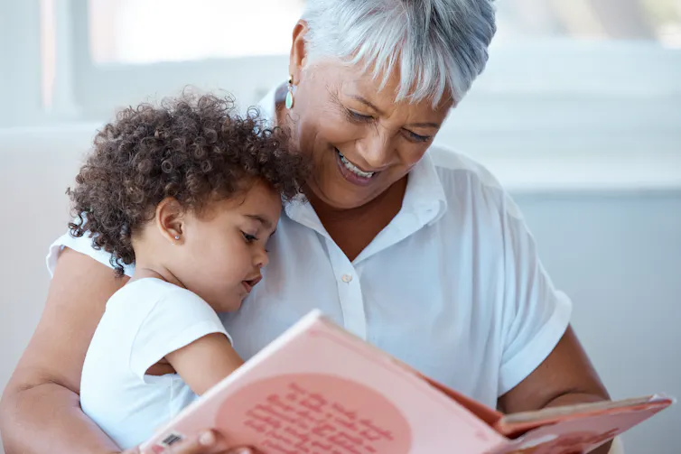 grandmother reading to a little boy sitting on her knee.