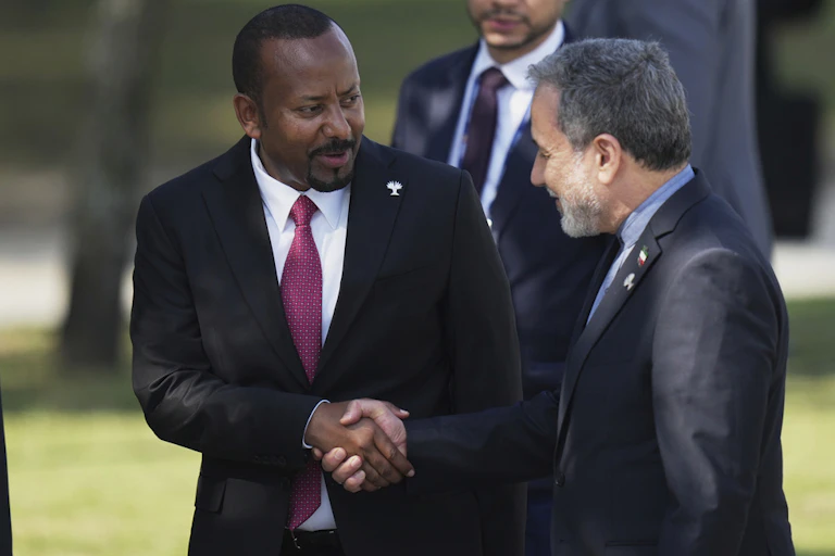 Two men in suits shake hands.