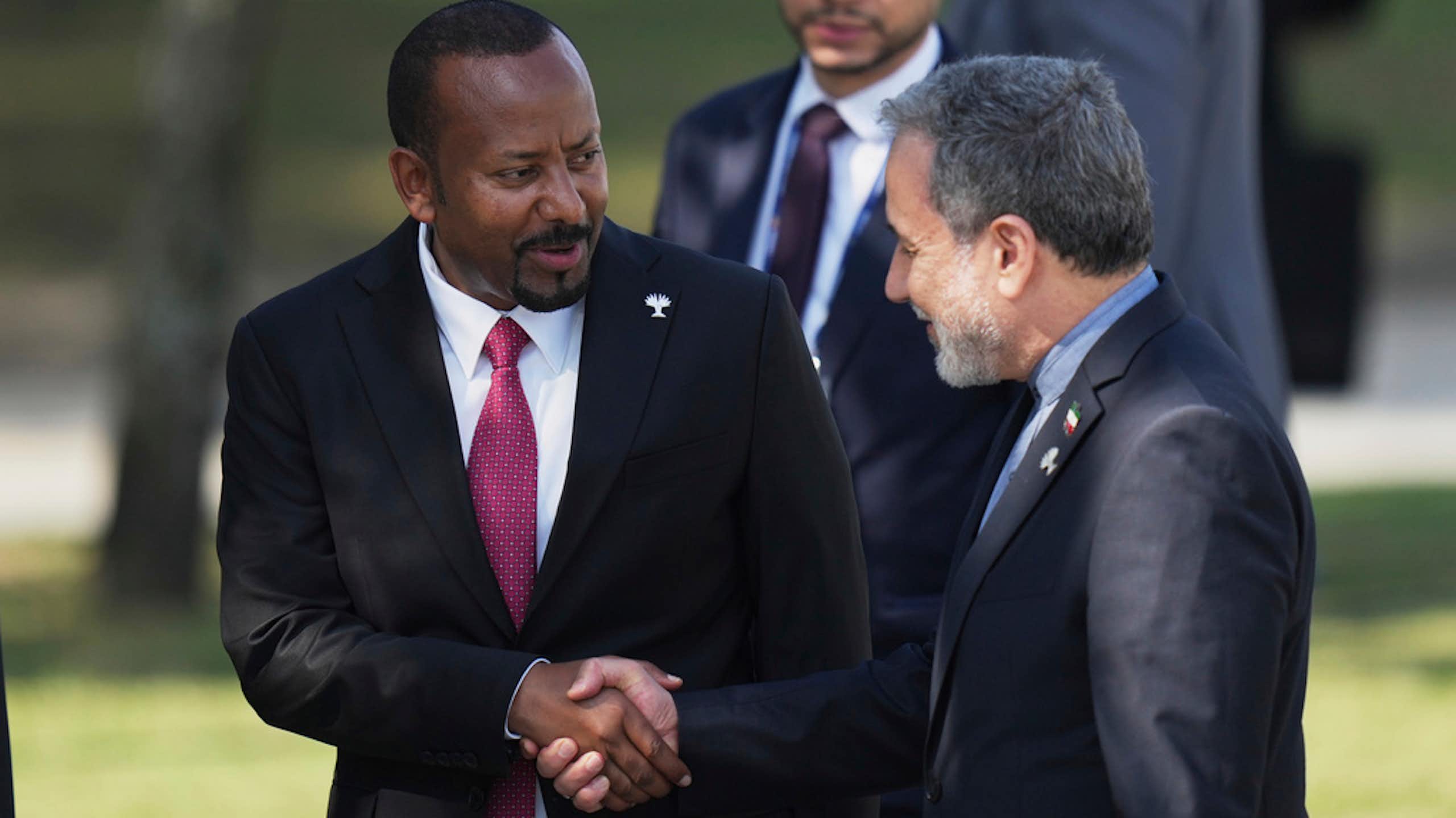 Two men in suits shake hands.