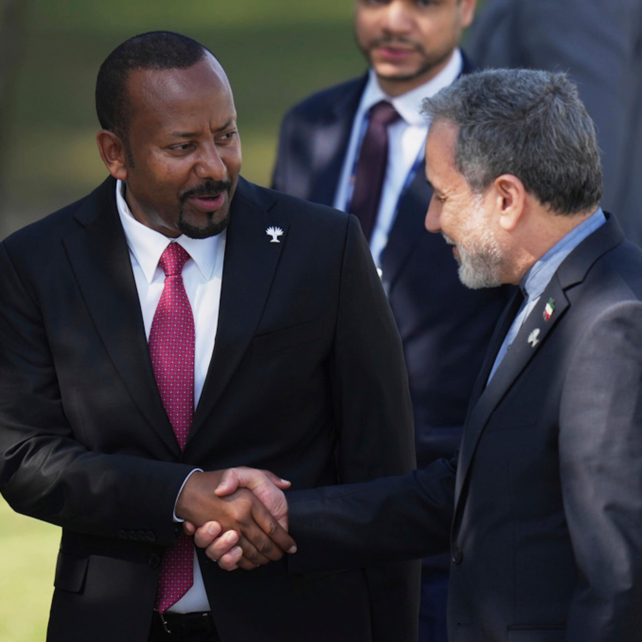 Two men in suits shake hands.