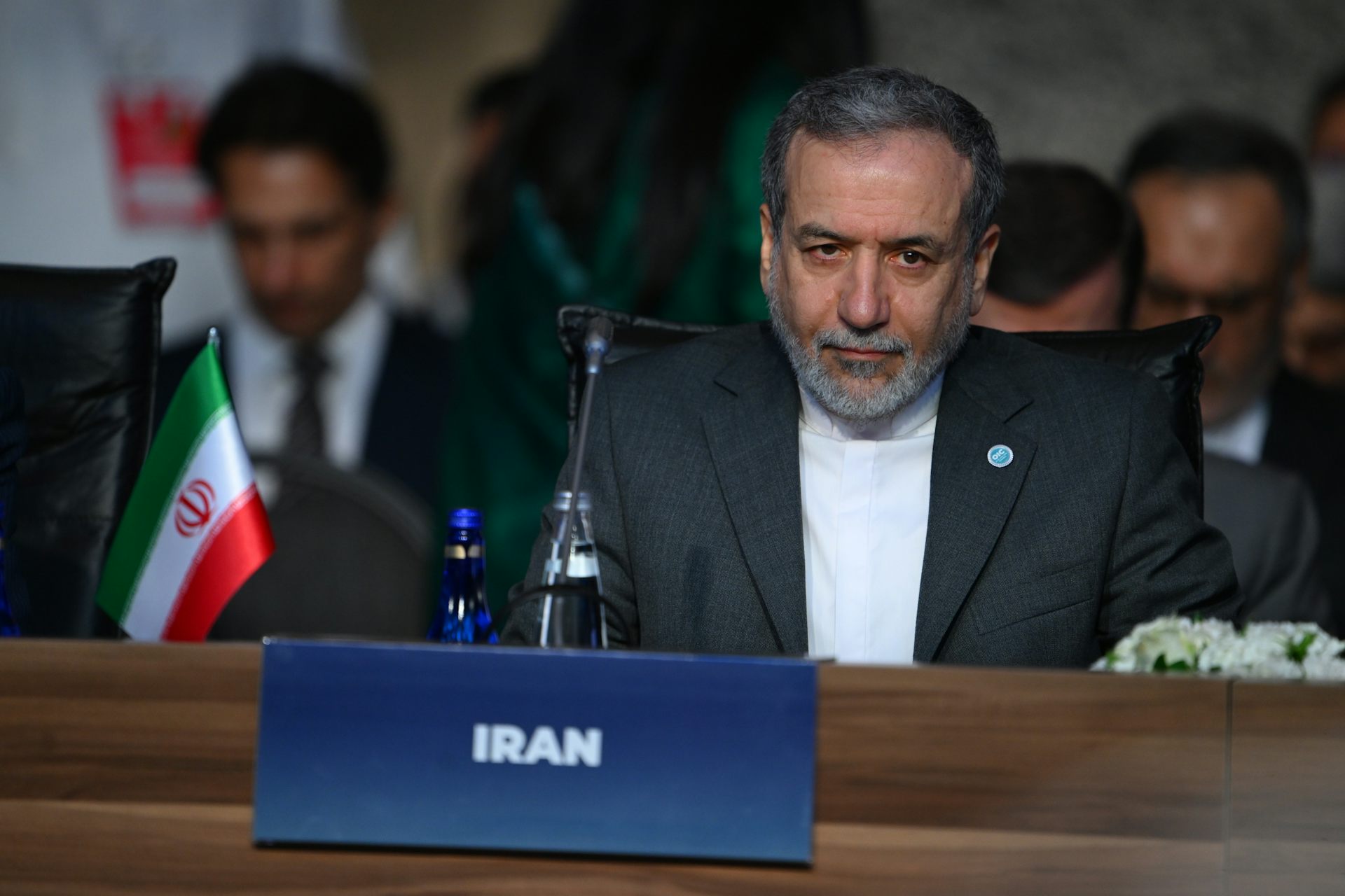 A man in a suit sits at a conference.