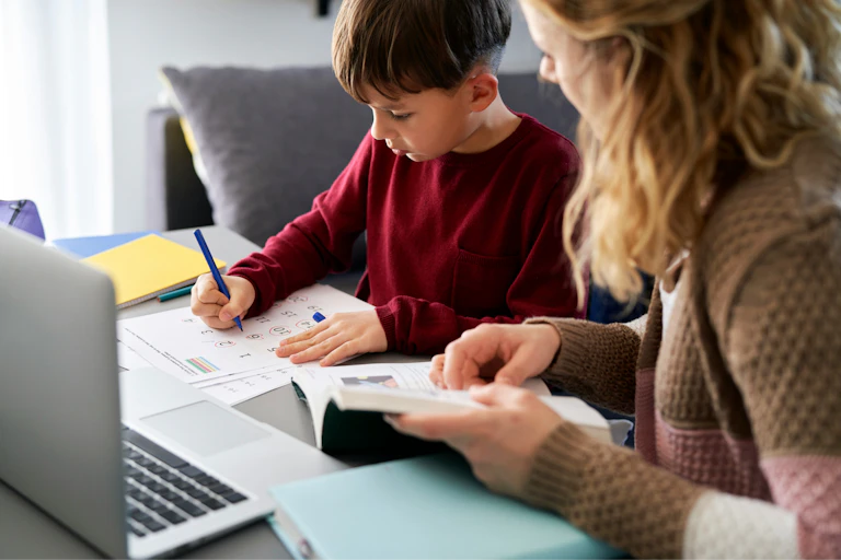 Un garçon fait des exercices de mathématique accompagné par sa mère