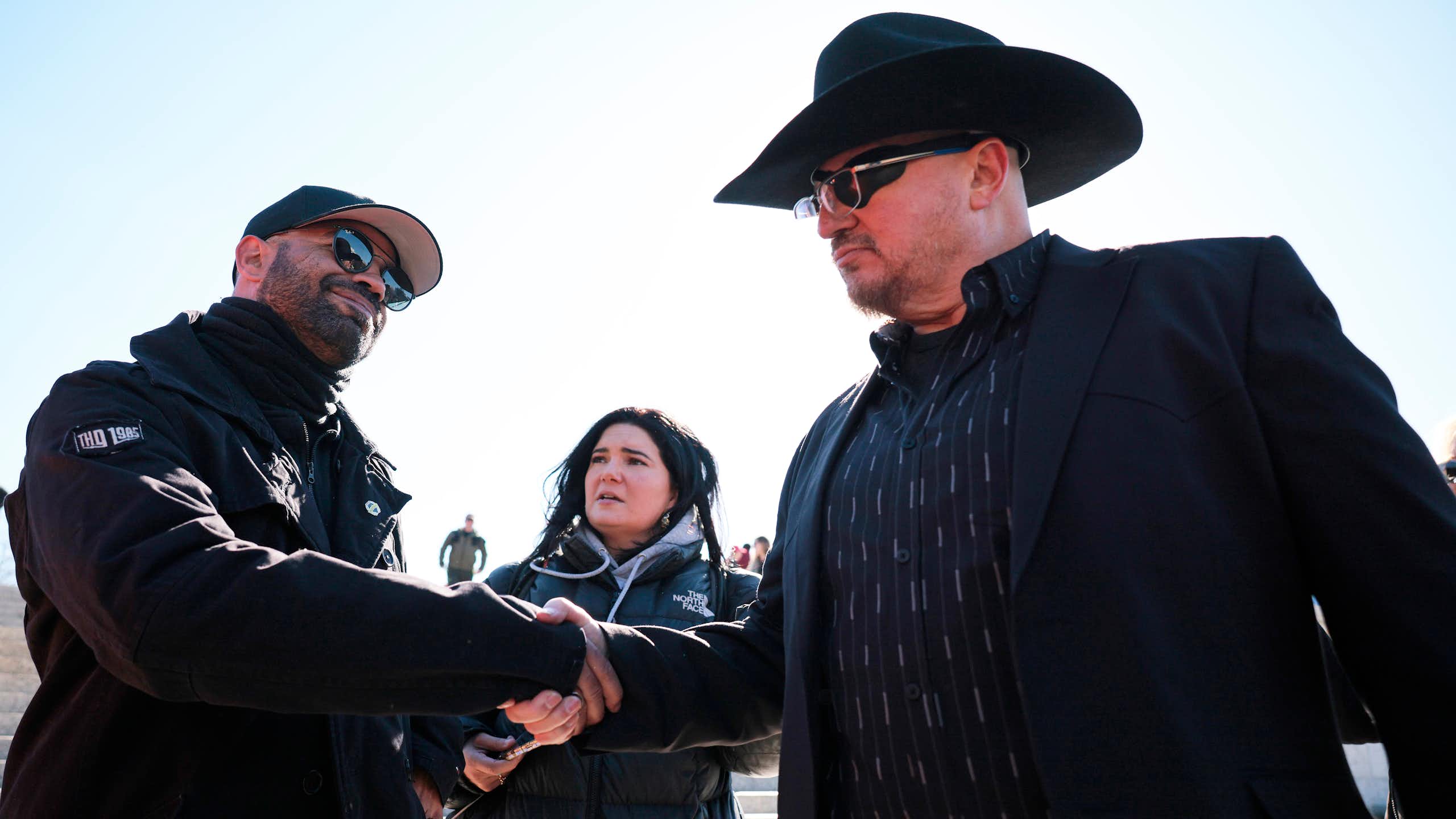 Two men dressed in black shake hands.