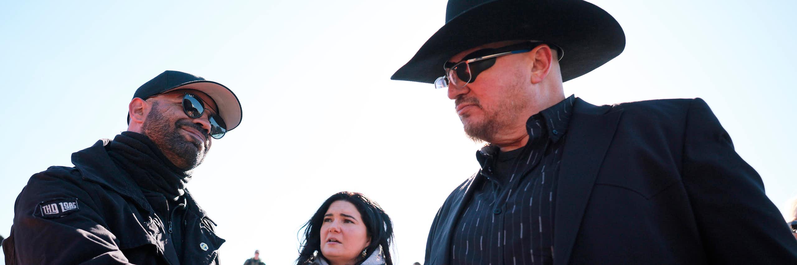 Two men dressed in black shake hands.