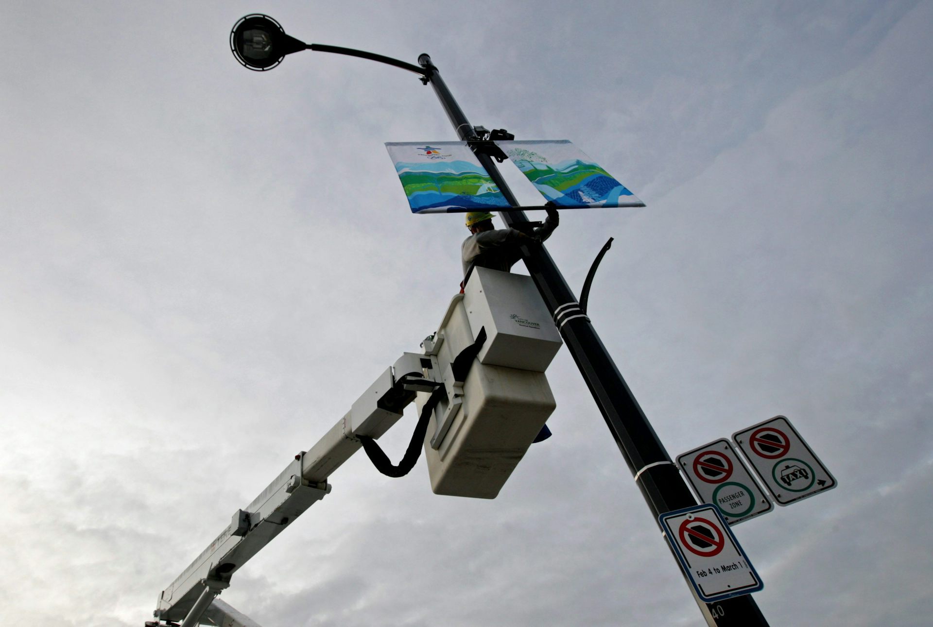 Un electricista en una grúa cuelga pancartas sobre un estandarte luminoso.