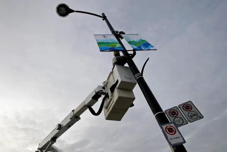 Un electricista en una grúa cuelga pancartas sobre un estandarte luminoso.